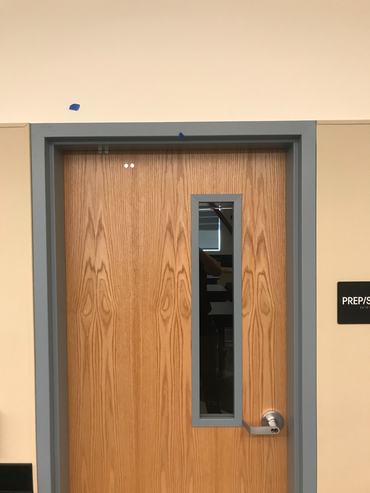 Installed wood commercial door with a vision panel and lever hardware