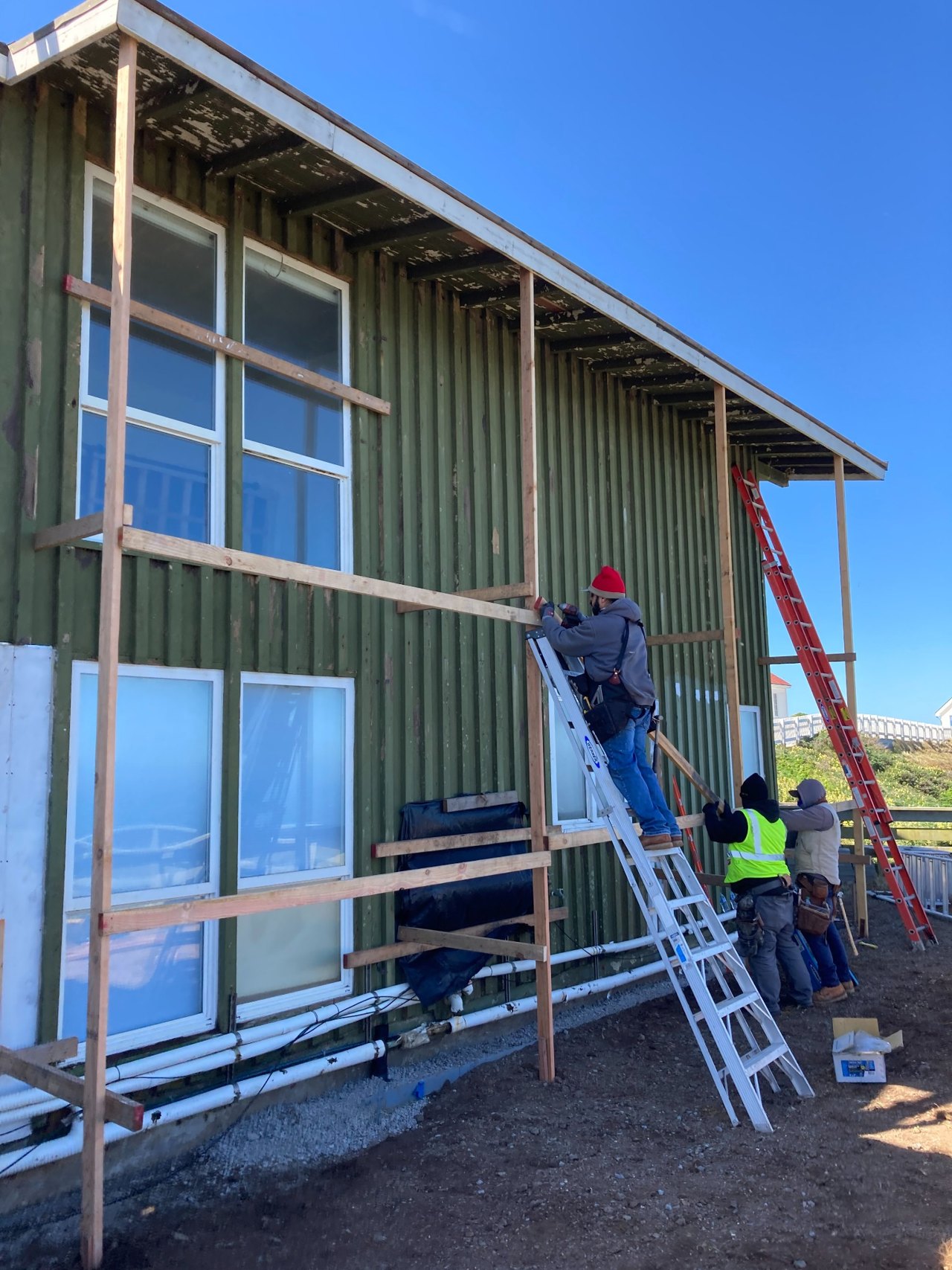 Worker on a ladder beside commercial windows during construction